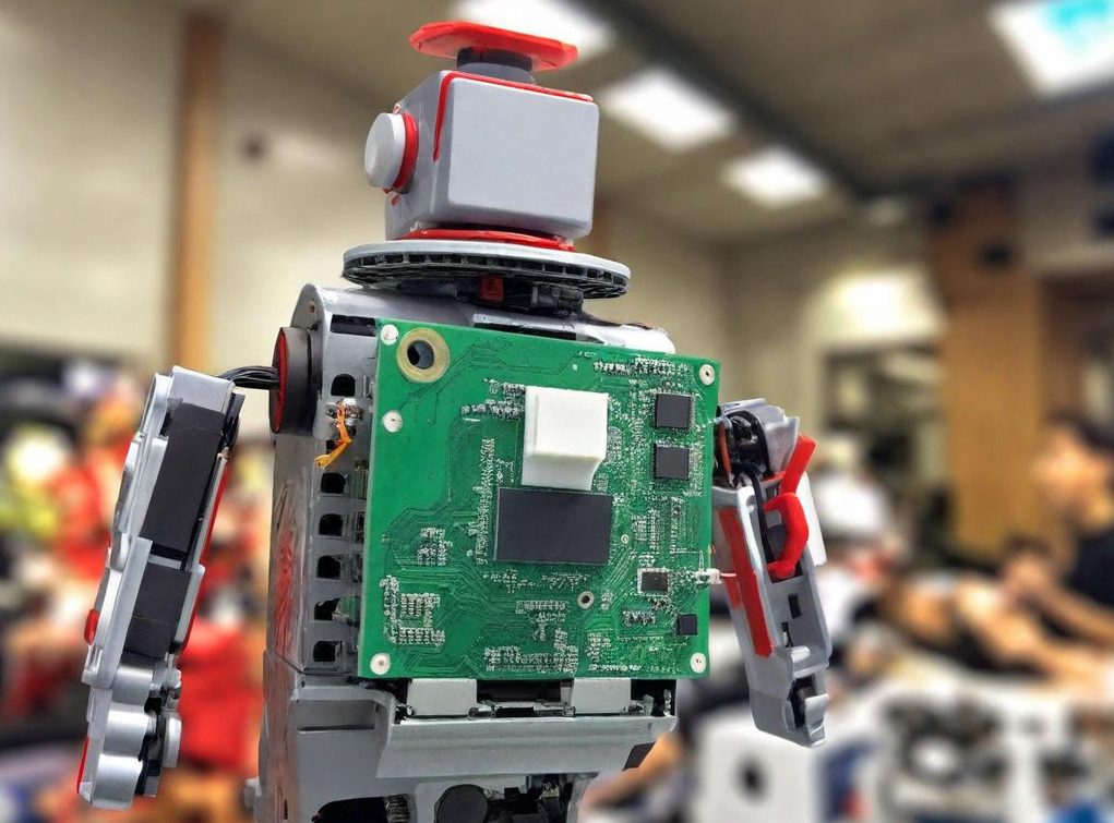 Bright Minds Weekend Club Home Page A small robot with a circuit board as its torso, set in a workshop environment.